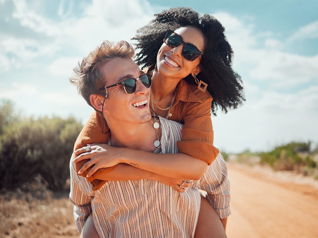 couple piggy back smiling while enjoying summer adventure together