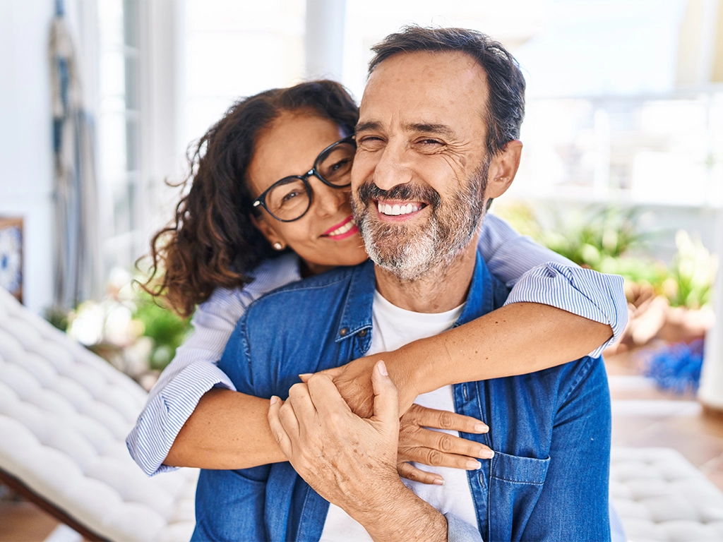 middle age couple smiling confident hugging each other sitting on hammock at terrace
