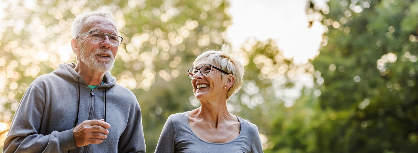 smiling senior couple jogging in the park